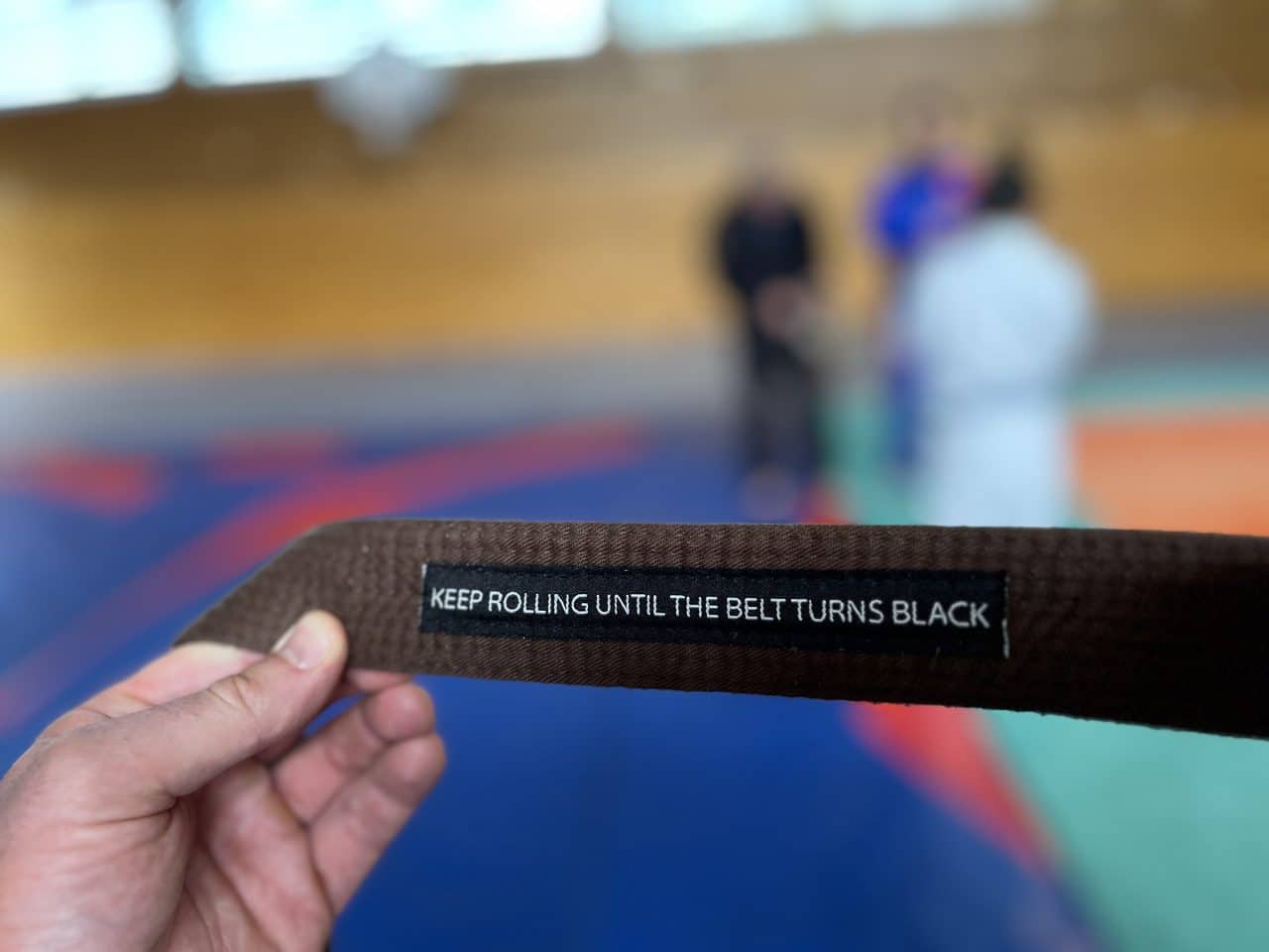 Ceinture marron avec inscription "Keep rolling until the belt turns black"
