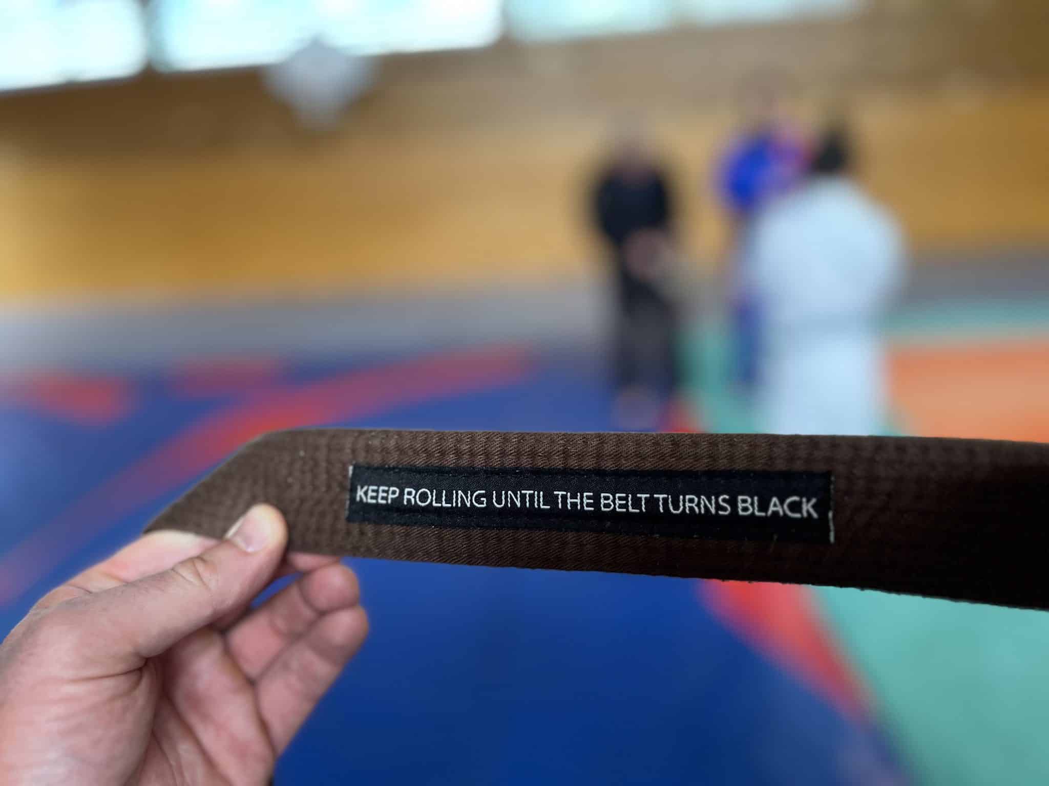 Ceinture marron avec inscription "Keep rolling until the belt turns black"