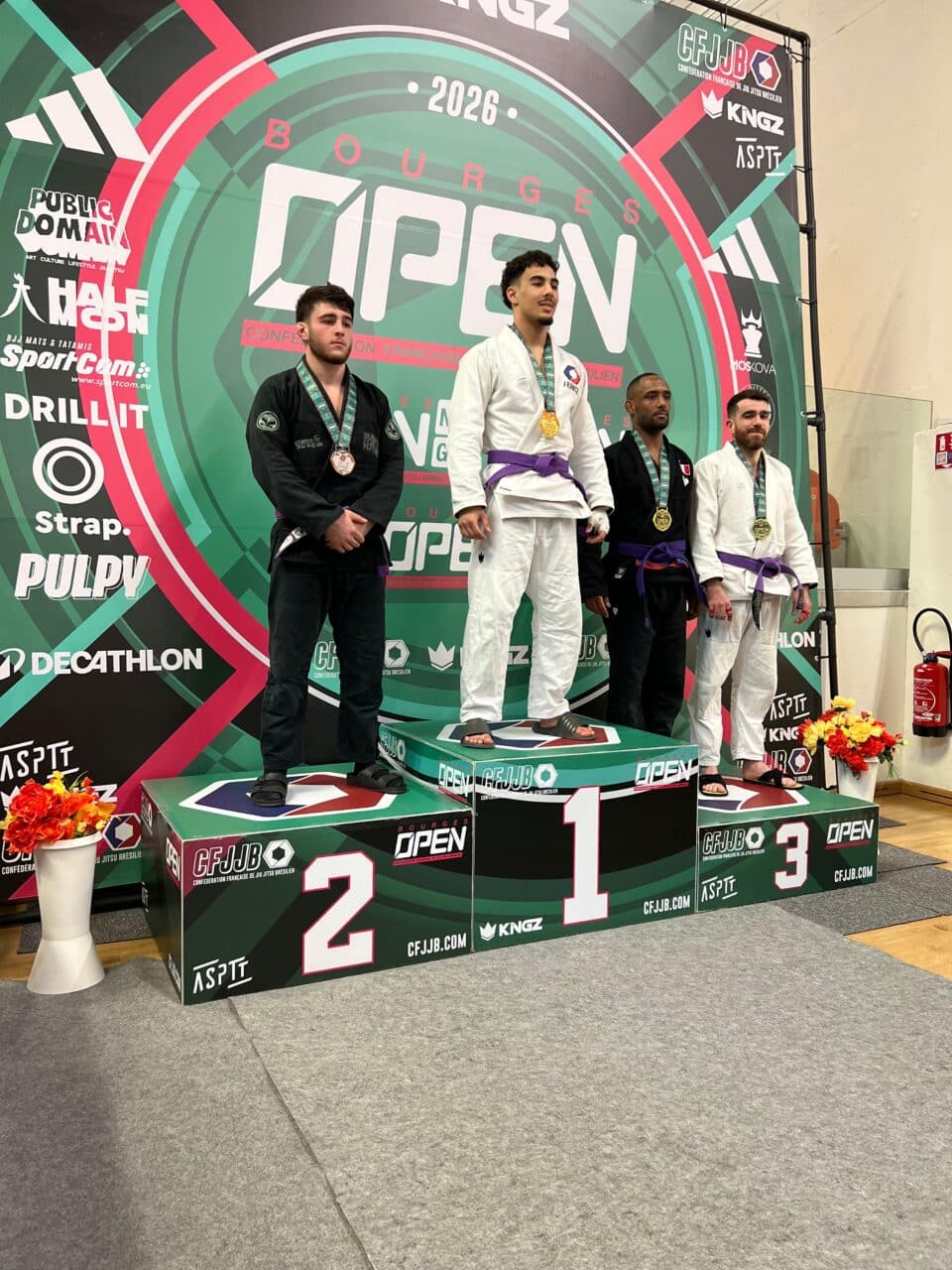 Podium compétition jiu-jitsu brésilien avec quatre athlètes médaillés
