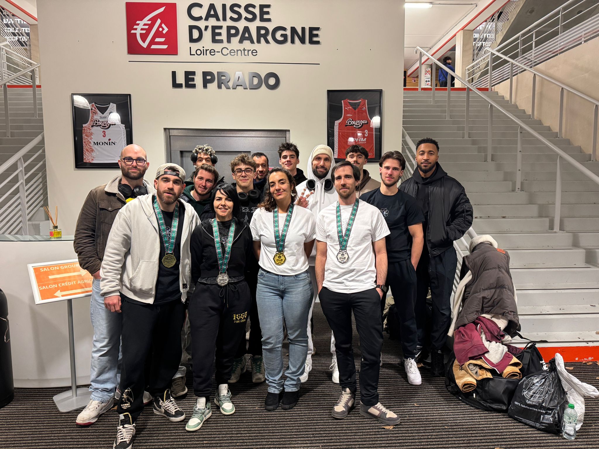 Équipe sportive avec médailles devant Caisse d'Épargne Le Prado