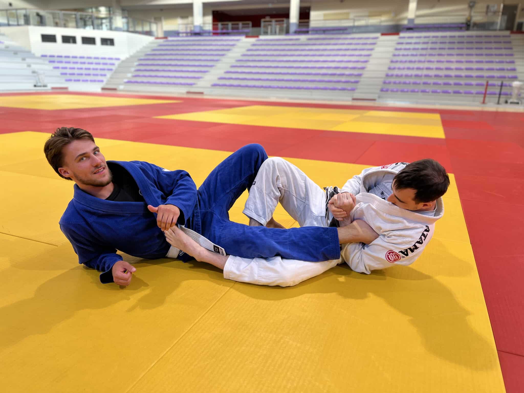 Deux judokas s'entraînent au sol dans un dojo
