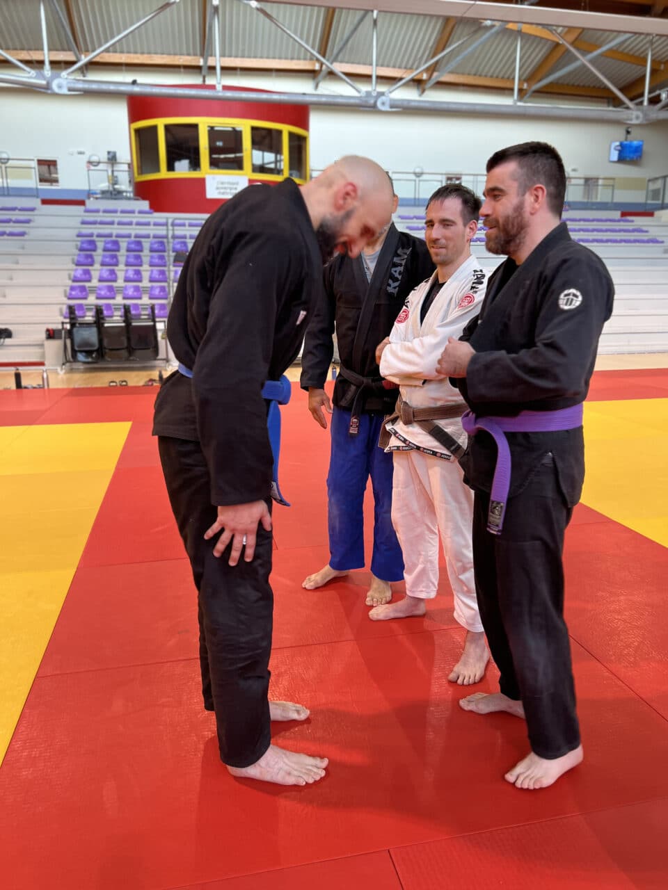 Quatre pratiquants de jiu-jitsu brésilien sur un tatami rouge
