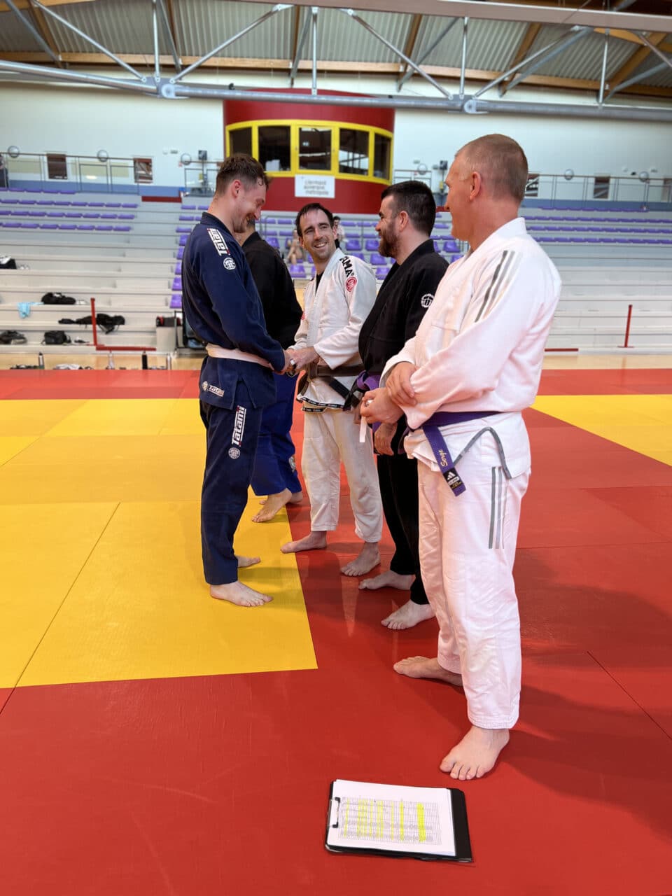 Quatre pratiquants de jiu-jitsu brésilien sur tatami en salle