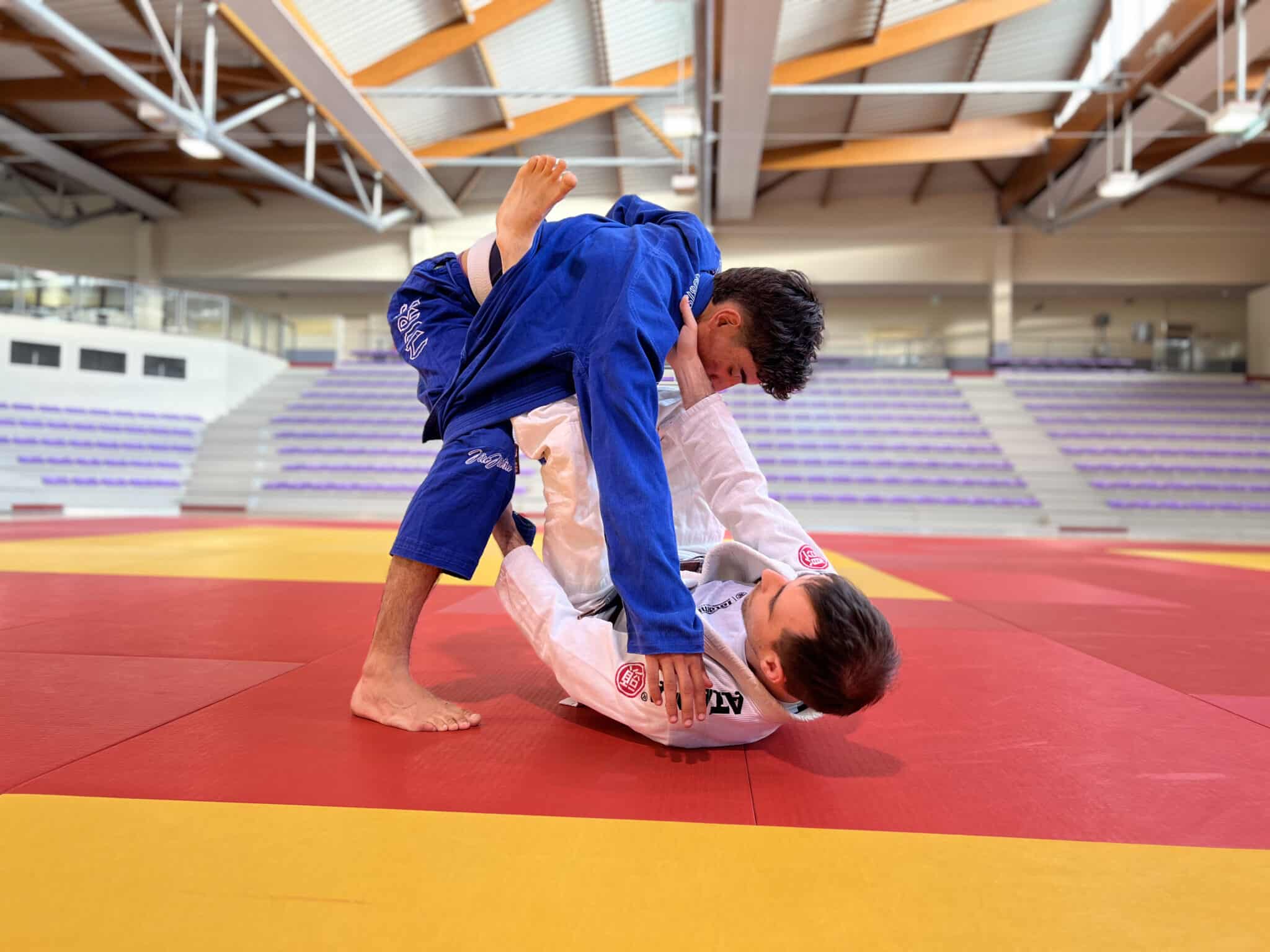 Deux judokas s'affrontent sur un tatami rouge et jaune