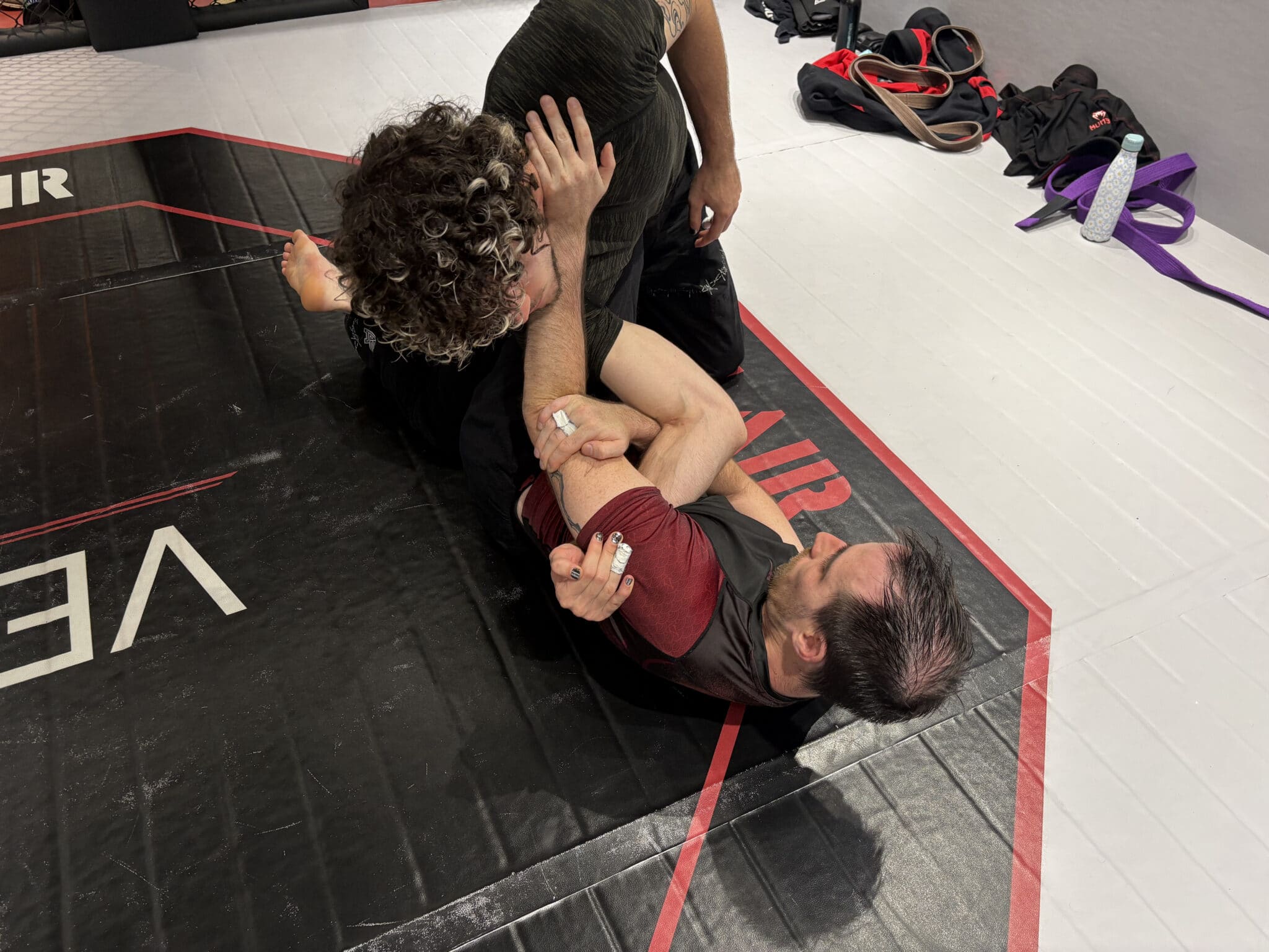 Deux pratiquants de grappling au sol en salle d'entraînement